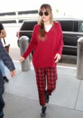 Dakota Johnson spotted in a red sweater with red and black checkered pants as she arrives at LAX airport in Los Angeles