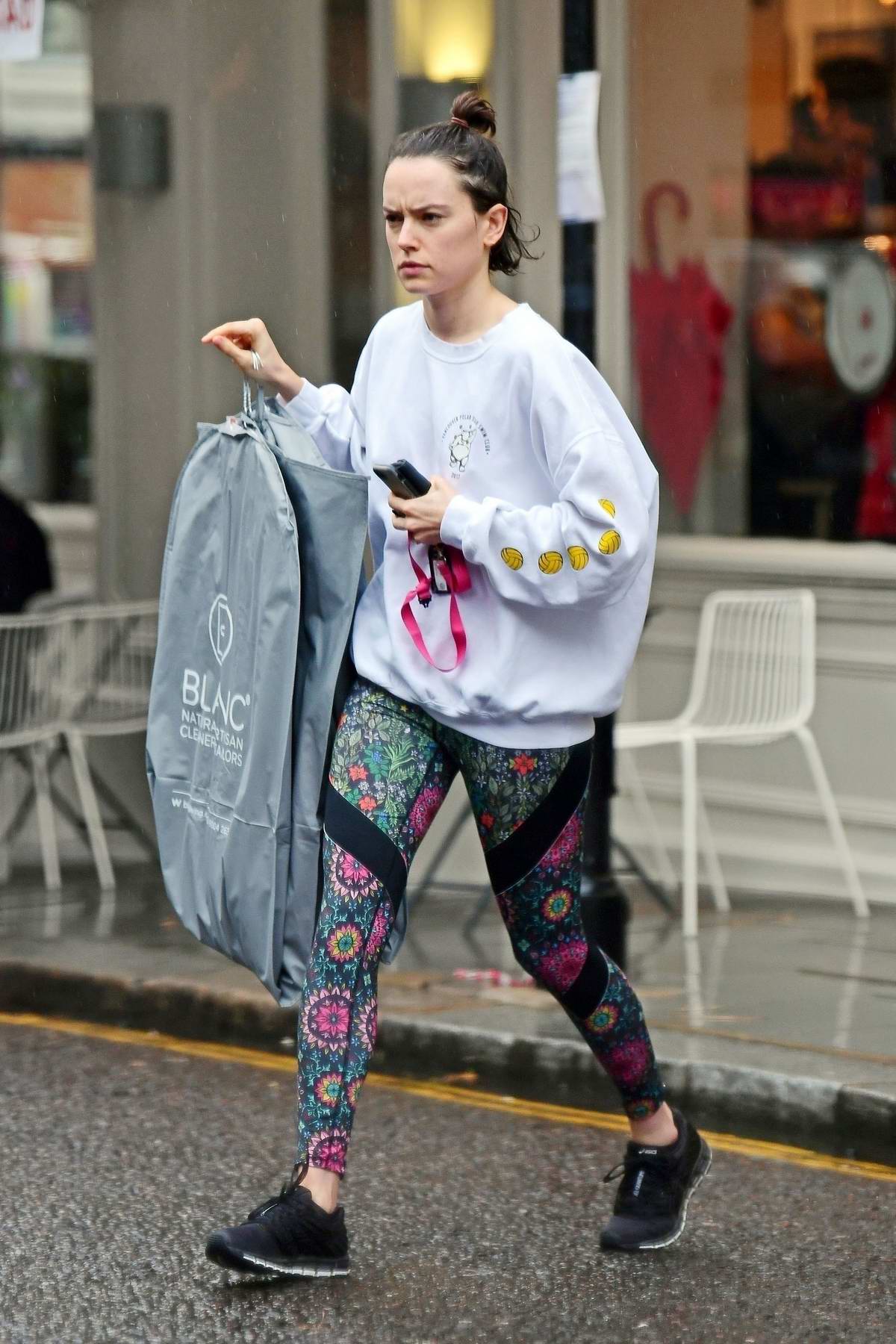 Daisy Ridley wears a white sweatshirt and colorful leggings while picking  up some dry cleaning in