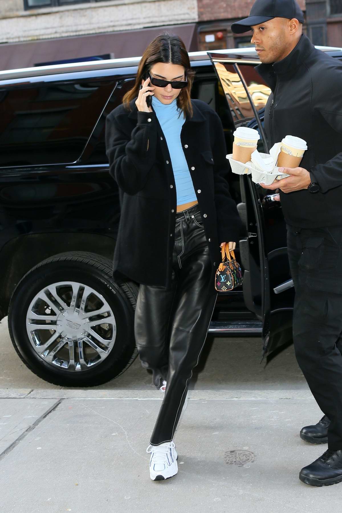Kendall Jenner wears a black jacket with a blue turtleneck and black  leather pants as she