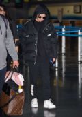 Selena Gomez keeps warm in a black puffer jacket, hoodie, and sweats while arriving at JFK Airport in New York City