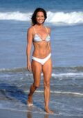 Brooke Burke seen wearing a white bikini while filming for her fitness app at the beach in Malibu, California