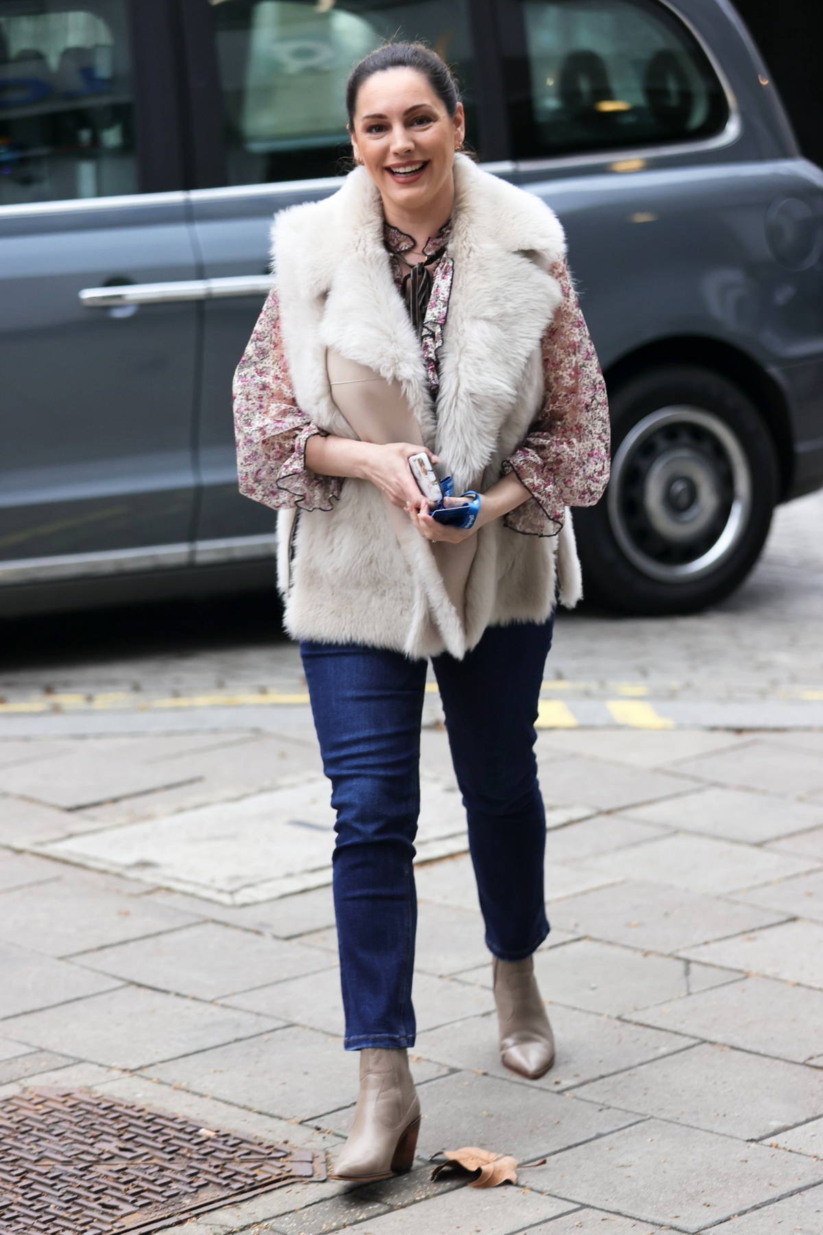 Kelly Brook looks stylish in a fur jacket over a frilly blouse and jeans as she arrives at Heart radio in London, UK