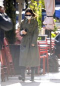 Emily Ratajkowski bundles up in a trench coat and black boots as she leaves her apartment in New York City