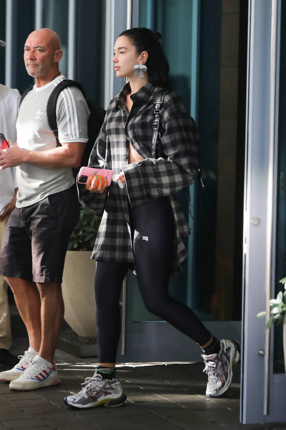 Dua Lipa wears black and grey plaid flannel shirt with black leggings while  heading out of