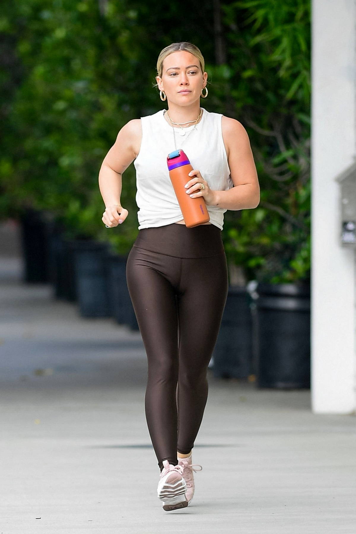 Hilary Duff looks fit in a white tank top and dark brown leggings