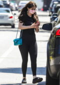 Zooey Deschanel wears a floral print mask with black top, leggings and sneakers as she leaves the gym in Brentwood, California