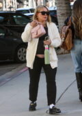 Hilary Duff wears a cream cardigan and black trousers while visiting a hair salon in West Hollywood, California